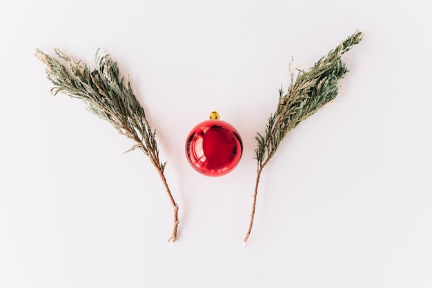 Fir tree branches with bauble on table 