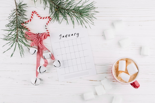 Fir tree branches with calendar and jingle bells 