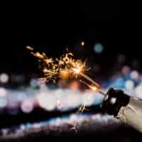 Free photo fire sparkler in champagne bottle on bokeh background at night