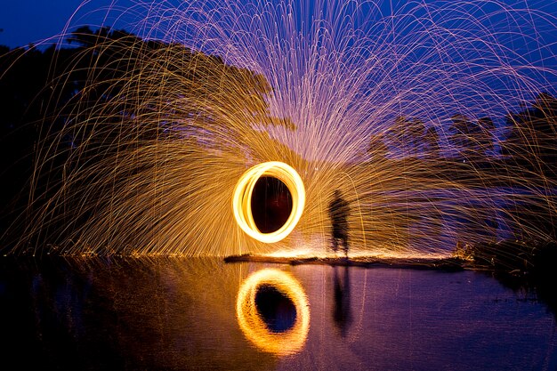 夜の街でスチールウールを紡ぐことで 熱く輝く花火のシャワー プレミアム写真