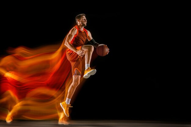 The fire tracks. Young caucasian basketball player of red team in action