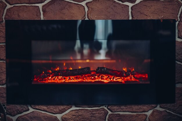 Fireplace with burning logs. Close-up of stony fireplace with burning or smoldering logs on fire.