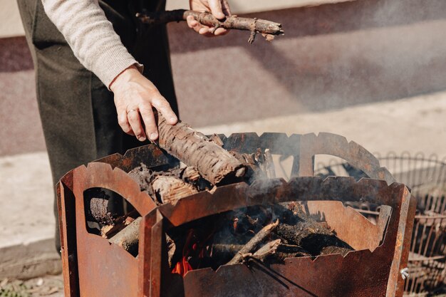 グリルの薪。男は肉を焼くためのたき火を発射します。