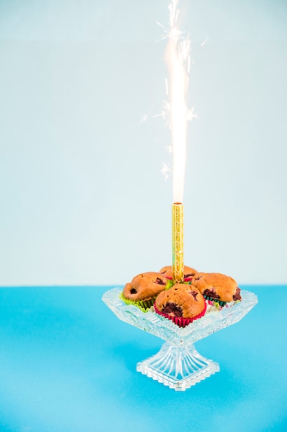 Firework sparkle in middle of cupcake on transparent cakestand against pink backdrop