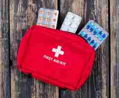 Free photo first aid kit with pills top view on a dark wooden background