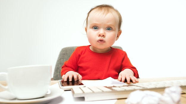 First sms. Child baby girl sitting with keyboard of modern computer or laptop in white studio