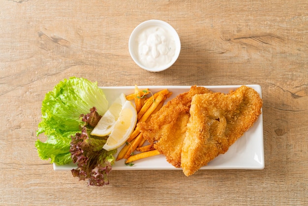 Рыба с жареным картофелем - жареное филе рыбы с картофельными чипсами и лимоном на белой тарелке