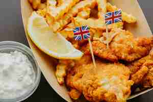 Foto gratuita fish and chips con salsa e bandiere della gran bretagna