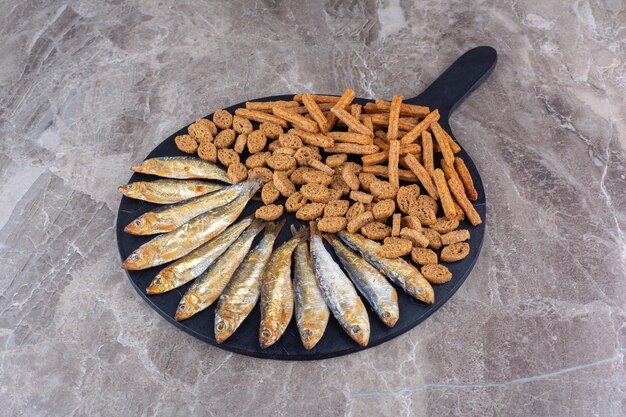 Fish and crunchy crackers on dark board. High quality photo