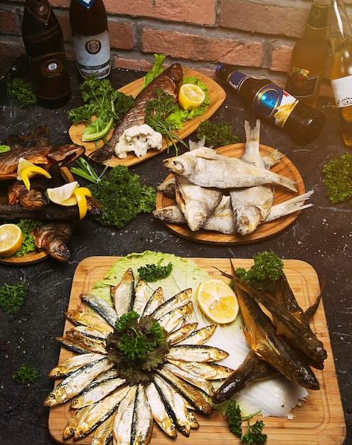 Fish dish cooking with various ingredients and fish sorts. Raw Sea bass with lemon, garlic, herbs and spices on cutting board. Healthy food or diet nutrition concept. 