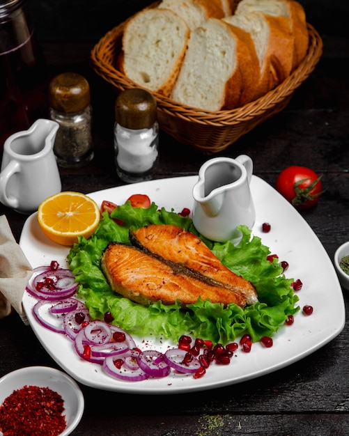 Fish fillet frilled and served in lettuce leaf with onion and lemon.