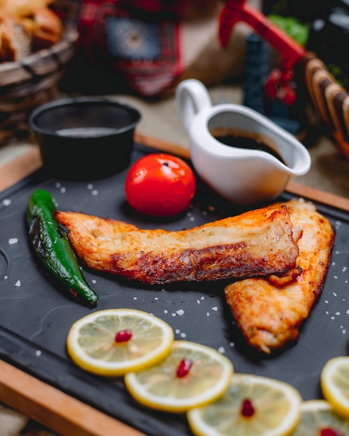 Kebab del pesce con la vista laterale della salsa del melograno del limone del pomodoro del pepe