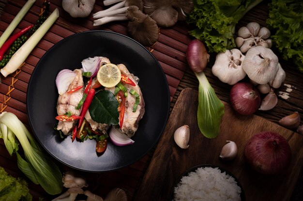 Рыбный салат с лаймом, чили, лемонграссом, луком, красным луком, петрушкой и листьями кафр-лайма в тарелке