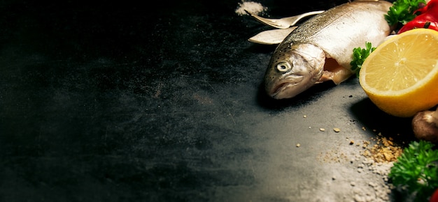 黒の背景に横にレモンと魚