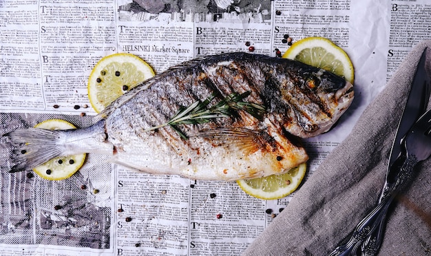 Free photo fish with lemon on newspaper