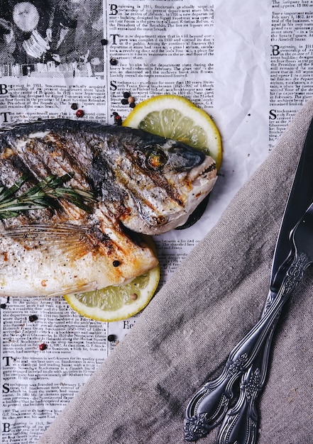 Free photo fish with lemon on newspaper