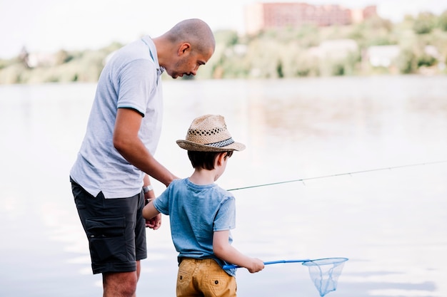 湖の近くで釣りをしながら息子を助ける漁師