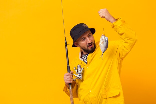 Fisherman holding fishing rod and looking at catch