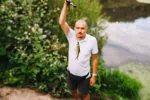 Free photo fisherman holding fresh caught fish at outdoors