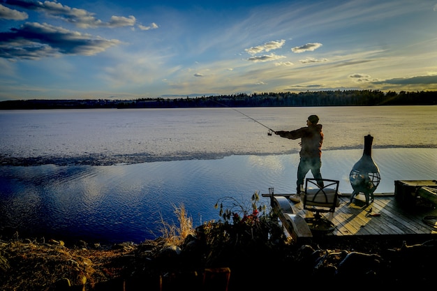 Foto gratuita pescatore su un molo che pesca pesce durante una bella giornata di sole