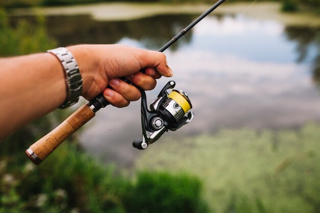 屋外で釣り竿を持っている漁師の手