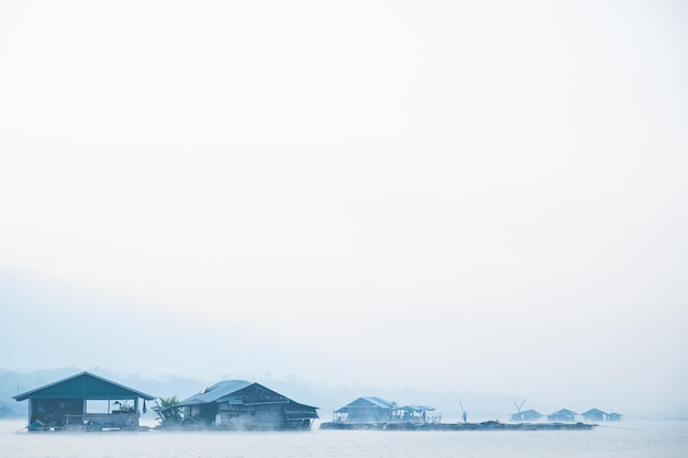 Деревянный дом рыбака, плавающий посреди голубого озера и холодного тумана