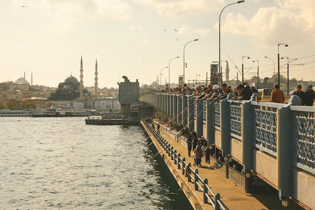 都市の景観と背景にガラタ塔とイスタンブールのガラタ橋の漁師