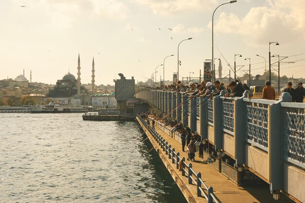 都市の景観と背景にガラタ塔とイスタンブールのガラタ橋の漁師