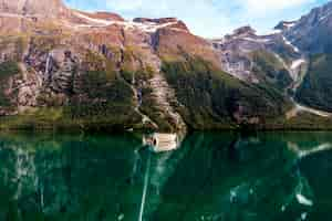 Free photo fishing boat on a still lake with high mountains in background