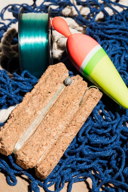 Fishing float and fishing line on cork board over the blue fishing net