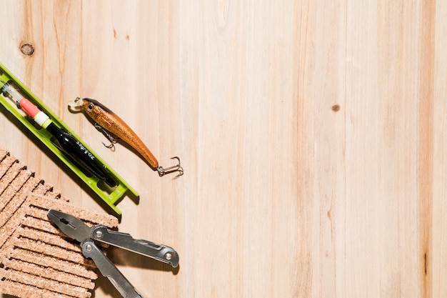 Fishing lure; fishing float; corkboard and plier on desk