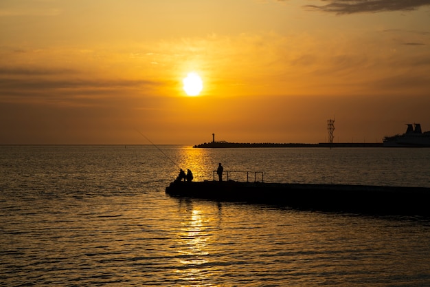 海での釣り 男性は夏の日没の夕方に釣ります プレミアム写真 海での釣り 男性は夏の日没の夕方に釣ります プレミアム写真