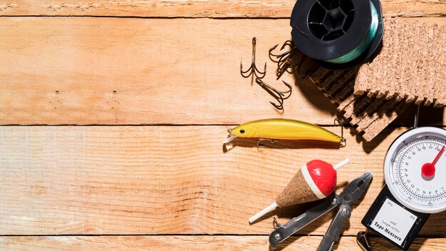 Fishing reel; fishing lure; fishing float; plier; corkboard and weighing scale on table