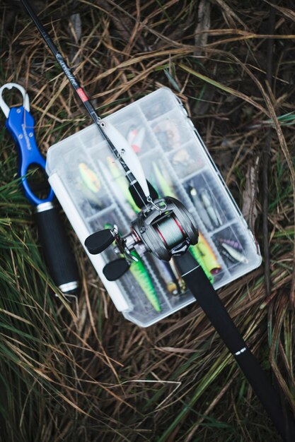 Fishing rod over the fishing lure transparent plastic box on grass