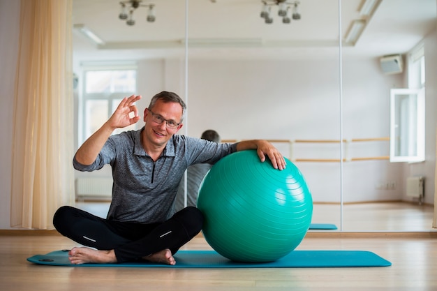 Fit adult man standing next to exercise ball