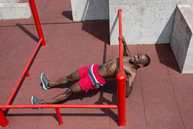 The fit athlete doing exercises at stadium. Afro or african american man outdoor at city. Pull up sport exercises. fitness, health, lifestyle concept