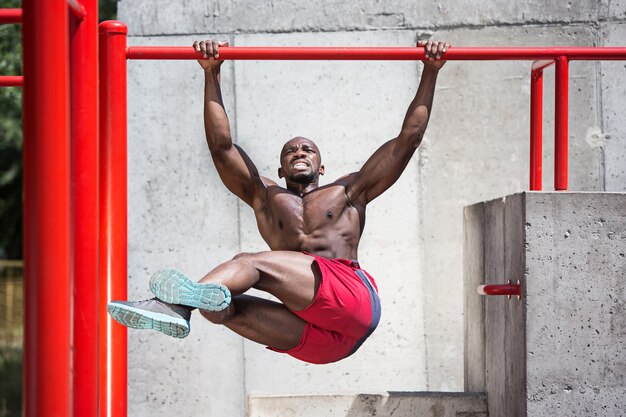 fit athlete doing exercises at stadium. Afro man outdoor at city. Pull up sport exercises. fitness, health, lifestyle concept