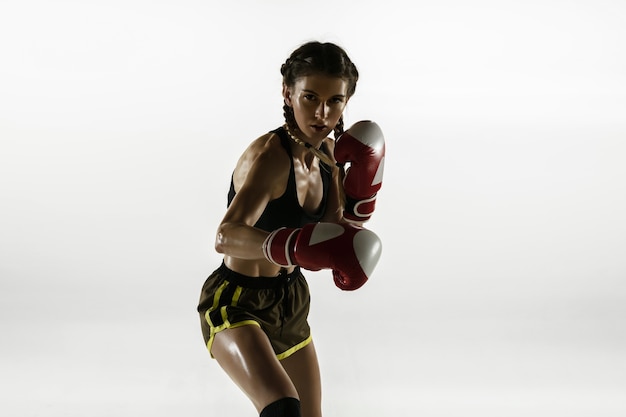 Free photo fit caucasian woman in sportswear boxing isolated on white  wall. novice female caucasian boxer training and practicing in motion and action. sport, healthy lifestyle, movement concept.