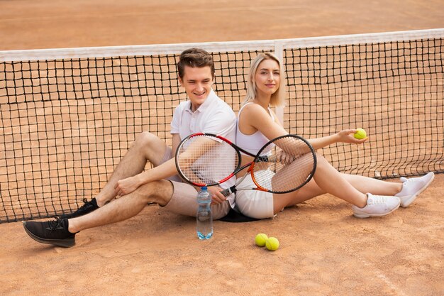 テニスコートの上に座ってフィットのカップル