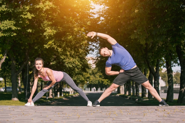 フィットネス女性と屋外公園でストレッチ体操をしている男性に合う