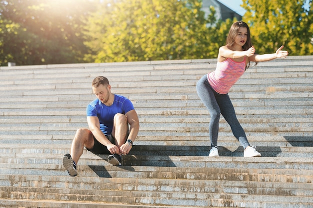 Free photo fit fitness woman and man doing stretching exercises outdoors at park