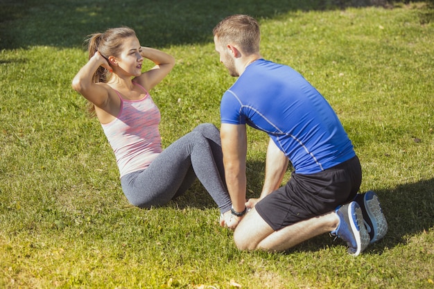 Fit fitness woman and man doing stretching exercises outdoors at park