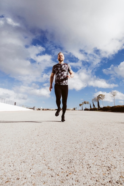 Fit healthy man running on road against sky