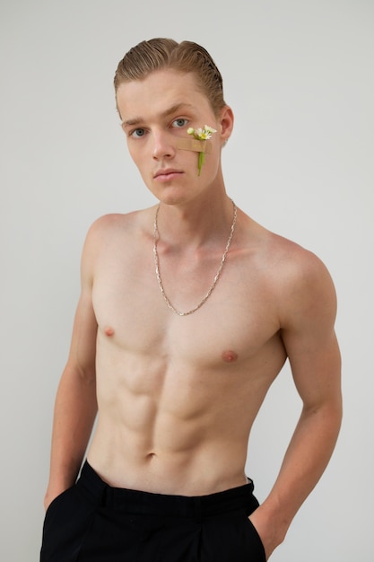 Fit man posing with flower on cheek medium shot