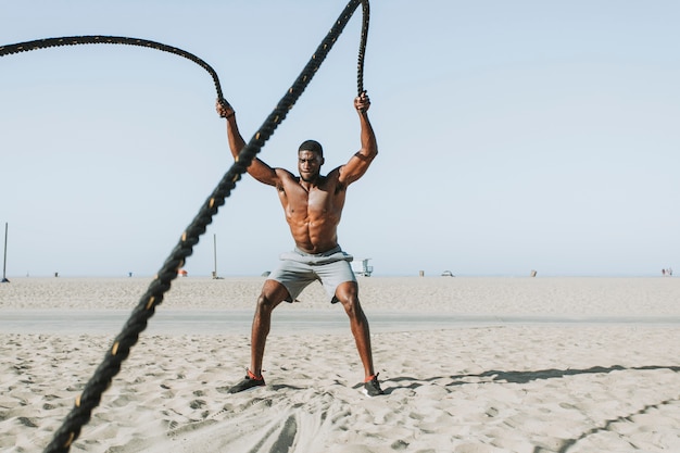 Free photo fit man working out with battle ropes