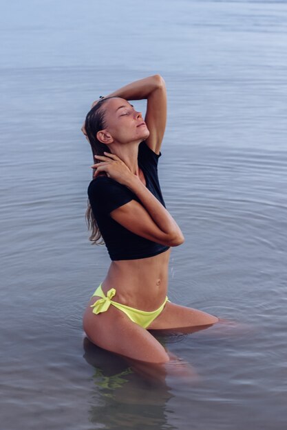 Fit tanned young caucasian Woman in sea at sunset