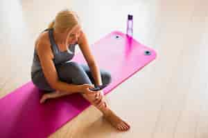 Free photo fit woman checking phone on yoga mat