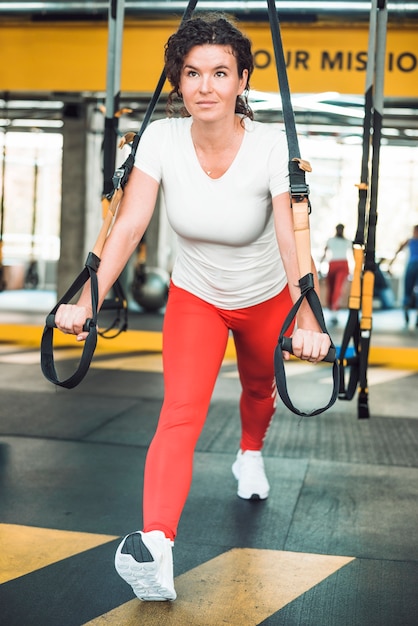 Fit woman doing exercise with fitness strap