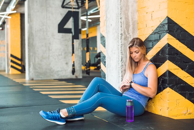 Fit woman looking at time on wrist watch in gym