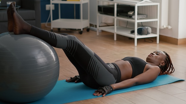 腹筋を曲げるフィットボールを使用して腹筋運動をしている黒い肌の女性にフィット